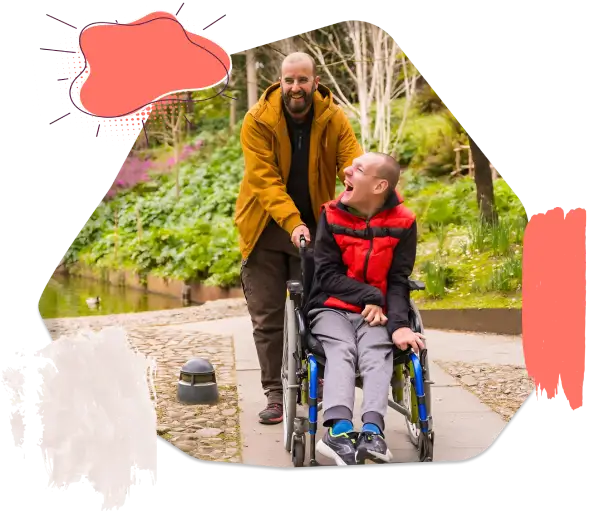 A Disable Boy is Laughing Sitting on Wheelchair and Man is Holding Wheelchair from Behind and Smiling